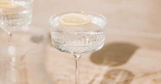 water with a lemon peel in wine glass on the dining table